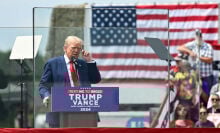 Donald Trump behind bulletproof glass at a campaign rally in 2024