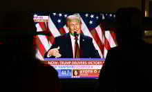A couple watch President Donald Trump's victory speech from a TV screen.