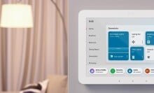 an amazon echo hub on a white wall inside of a home. it displays the time, lights, ceiling fan, vacuum, locks, and more