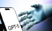 A robotic hand reaches for a phone displaying the text "GPT-5".
