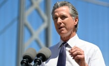 California governor Gavin Newsom speaks at a podium in front of the Bay Bridge.
