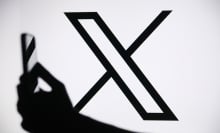 x logo behind a hand holding a phone