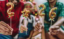 Festive family celebrating the new year at home, holding golden balloons with the numbers 2026. Christmas tree and holiday decorations in the background, joyful and warm atmosphere. Concept of family togetherness, holidays, festive season, new beginnings, 2026 celebration