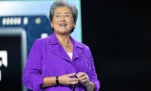 AMD CEO Lisa Su smiling on stage in front of an image of a Ryzen chip.