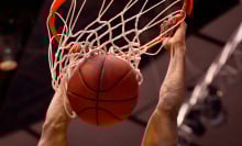 Male basketball player dunks the ball with two hands