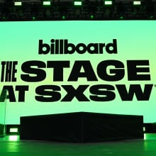 A glowing green screen on a stage that reads "Billboard. The stage at SXSW."