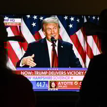 A couple watch President Donald Trump's victory speech from a TV screen.