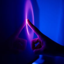 A finger taps a glowing purple and blue touch screens 