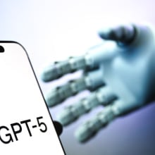 A robotic hand reaches for a phone displaying the text "GPT-5".
