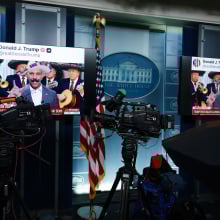 Two monitors in the White House press room show a screenshot of a post by President Trump sharing an AI edited video of House Minority Leader Hakeem Jeffries.
