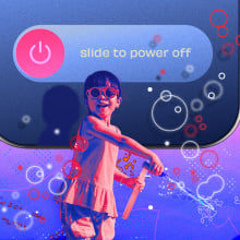 Child smiling and blowing bubbles while phone behind them is powered off. 
