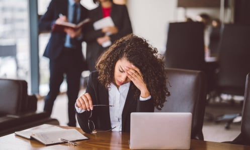 Woman sits at her office desk, looking stressed out. 
