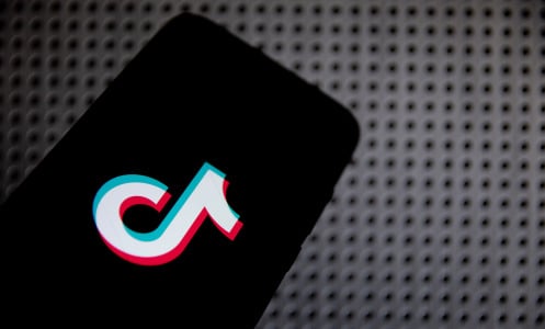 TikTok logo on a phone, against a gray background. 