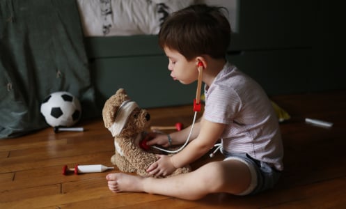 Boy plays with a stuffed bear.