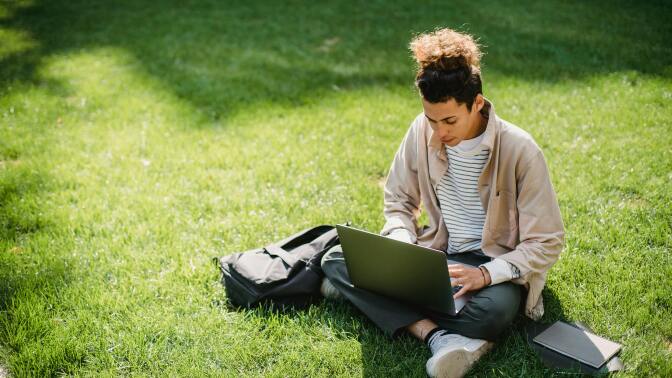 Man sat on grass with laptop