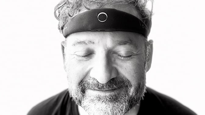 A man with the elemind headband, smiling with eyes closed