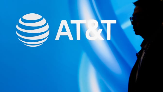 The silhouette of a man standing in front of a blue AT&T logo.