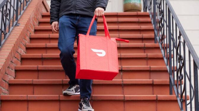 Person holding a DoorDash bag on a flight of stairs