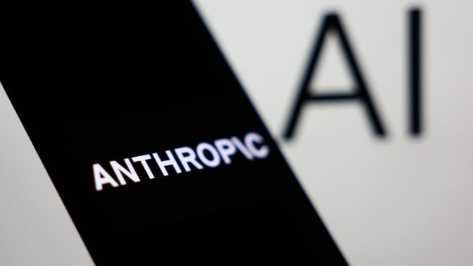 Anthropic logo displayed on a phone screen and AI sign displayed on a screen