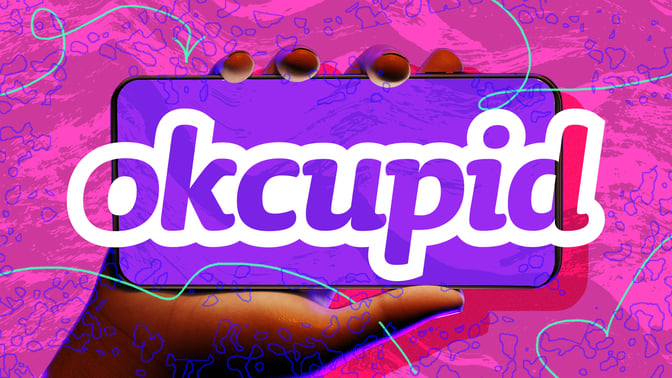 Hand holding phone with OkCupid logo against abstract background