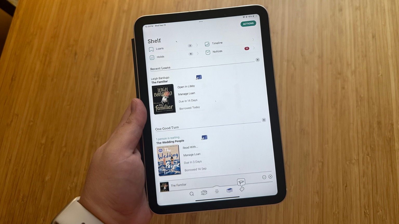 A hand holding an iPad Mini with the Libby app open