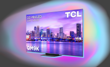 TCL QM9K TV arranged on gray backdrop with burst of color