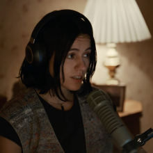 A woman sits in a room wearing headphones.