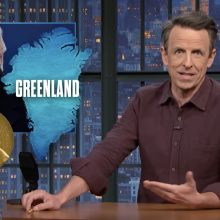 A man sits behind a talk show desk. An image of the president is in the top-left.