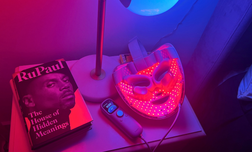 Shark red light face mask, lamp, and book on nightstand