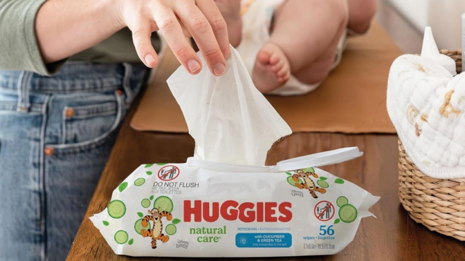 Parent changing baby on table and grabbing wipe with hand