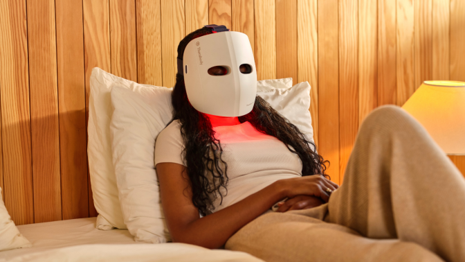 woman sitting on a bed wearing the TheraFace Mask Glo